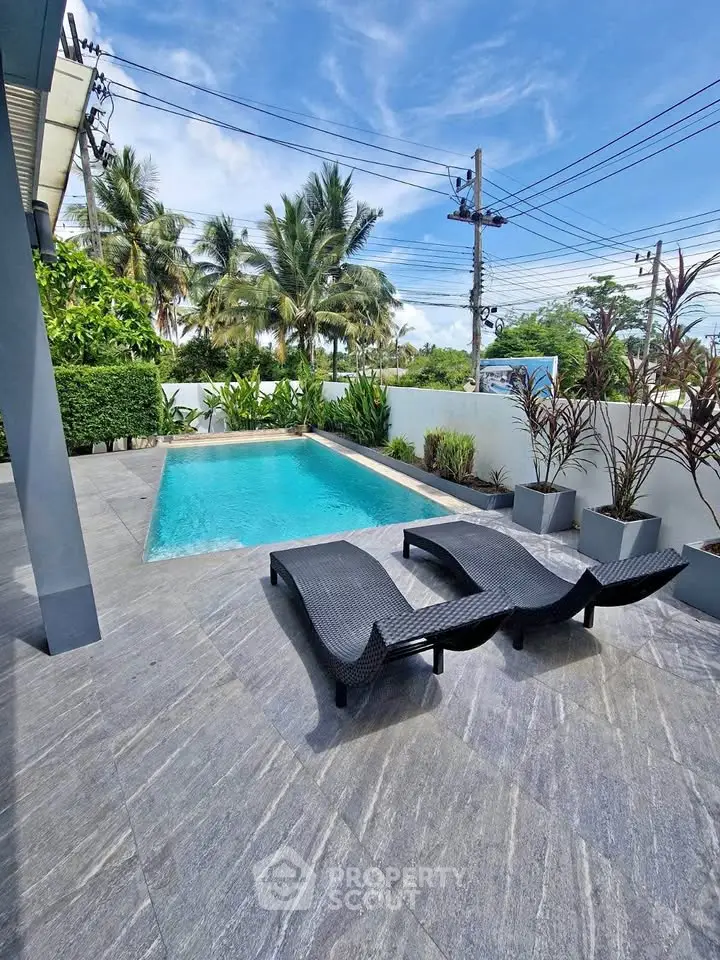 Luxurious outdoor pool area with modern loungers and lush greenery, perfect for relaxation and leisure.