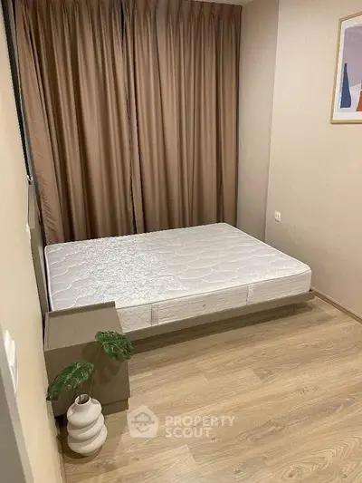 Cozy bedroom with minimalist decor and wooden flooring, featuring a comfortable bed and elegant curtains.