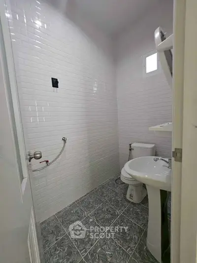 Compact bathroom with white tiles and modern fixtures, ideal for small spaces.