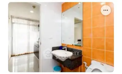 Modern bathroom with orange tiles and sleek fixtures, featuring a large mirror and natural light.