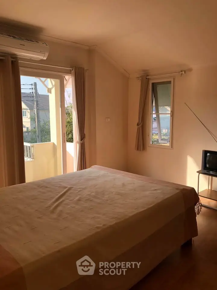 Cozy bedroom with natural light and balcony access in a serene neighborhood.