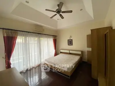 Spacious bedroom with elegant ceiling fan and large windows for natural light