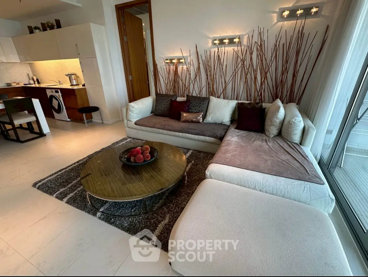 Modern living room with stylish decor and open kitchen layout, featuring cozy seating and elegant lighting.