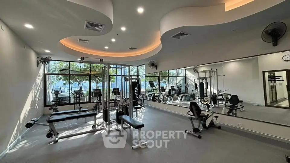 Modern gym with state-of-the-art equipment and large mirrors in a luxury building.