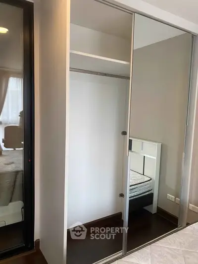 Modern bedroom with mirrored sliding closet doors and cozy bed setup.