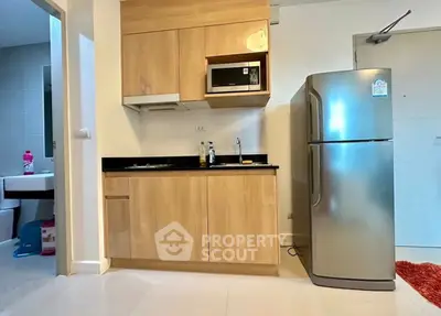 Modern kitchen with wooden cabinets and stainless steel fridge in compact apartment