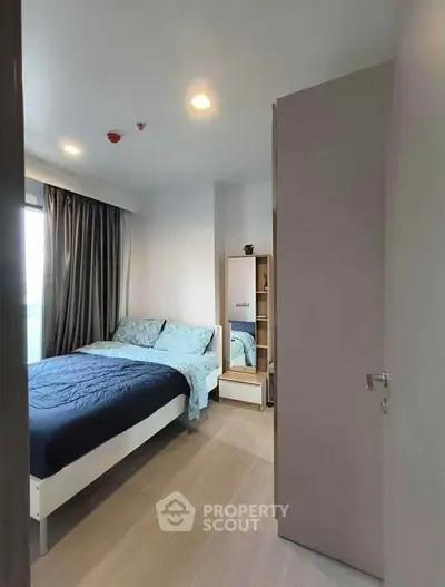 Modern bedroom with stylish decor and natural light, featuring a cozy bed and sleek furnishings.