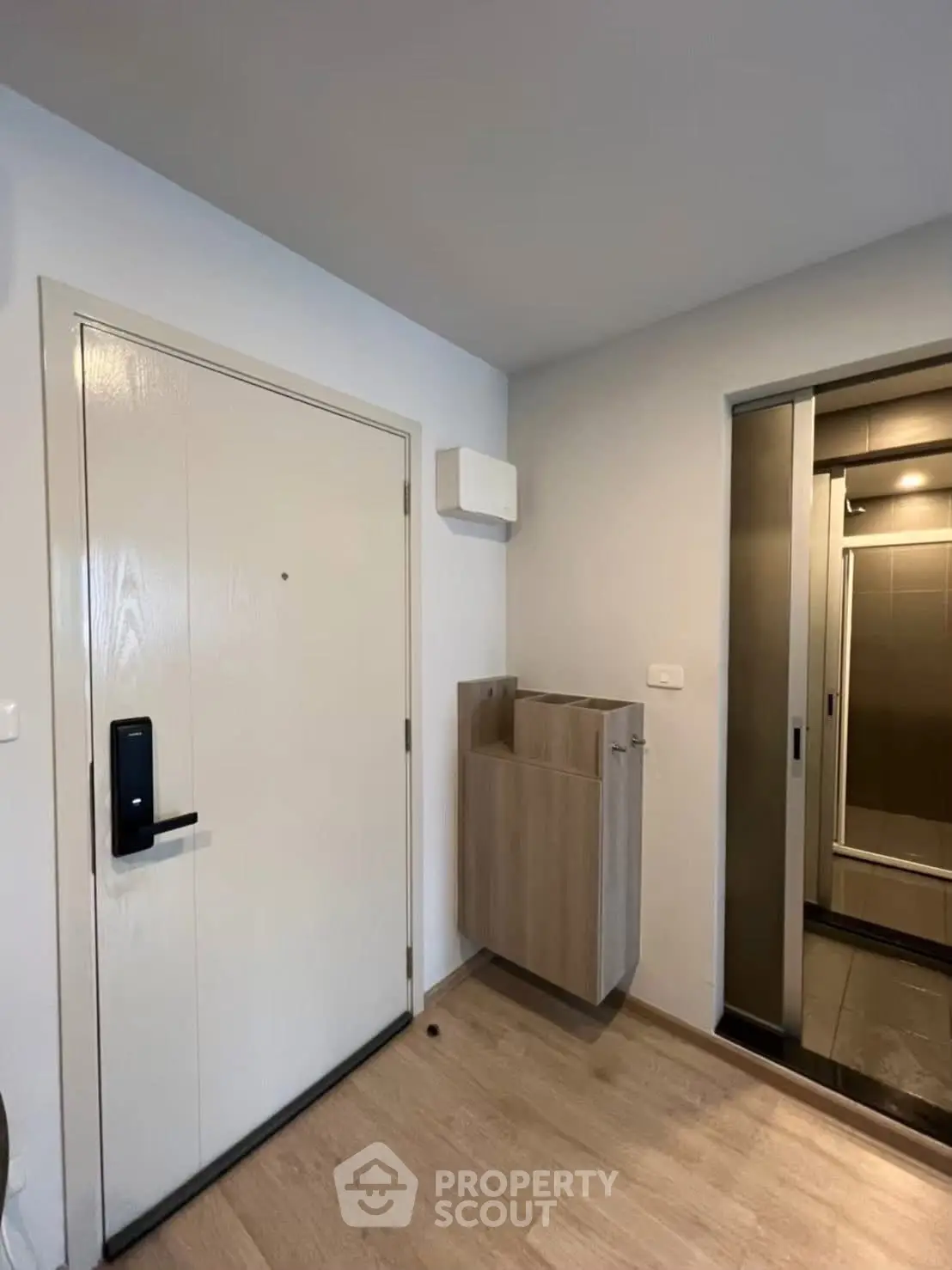Modern apartment entrance with sleek wooden flooring and stylish storage unit.