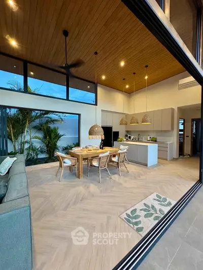 Stunning open-plan living room with modern kitchen and dining area, featuring high ceilings and elegant decor.