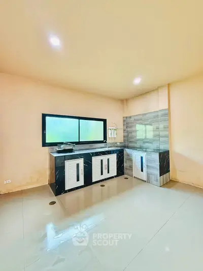 Spacious modern kitchen with sleek black countertops and ample natural light.