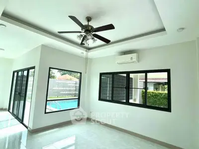 Spacious living room with ceiling fan and pool view, perfect for modern living.