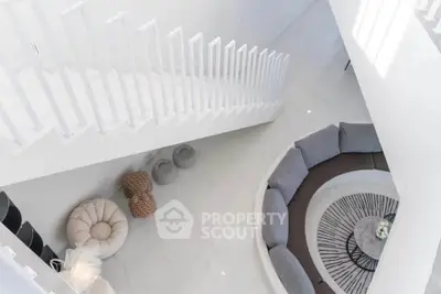 Stunning modern living room with unique circular sofa and elegant staircase view.