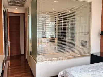 Modern bedroom with glass-enclosed bathroom and wooden flooring