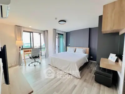 Spacious modern bedroom with balcony and study area, featuring elegant decor and natural light.