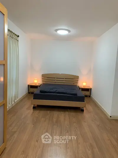 Spacious bedroom with wooden flooring and cozy lighting, perfect for relaxation.