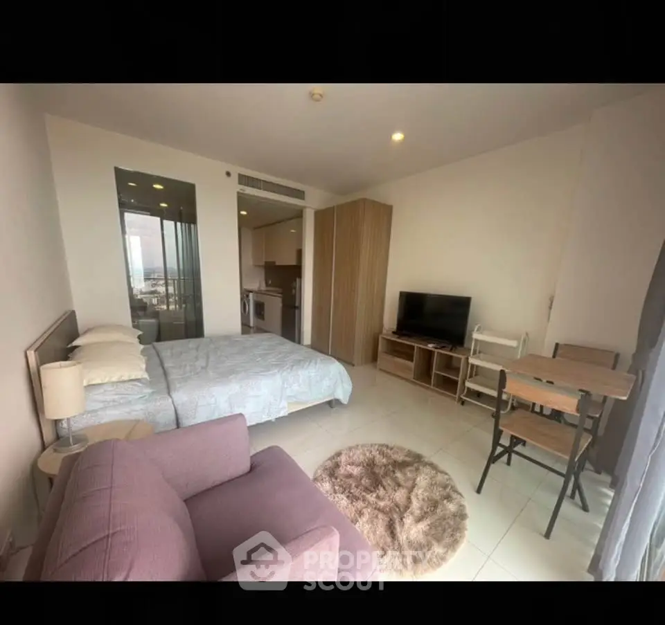 Modern studio apartment with cozy furnishings and open layout, featuring a comfortable bed, sofa, and dining area.