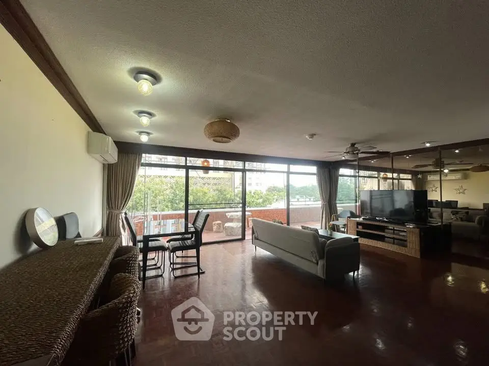 Spacious living room with large windows and balcony access, perfect for entertaining and relaxation.