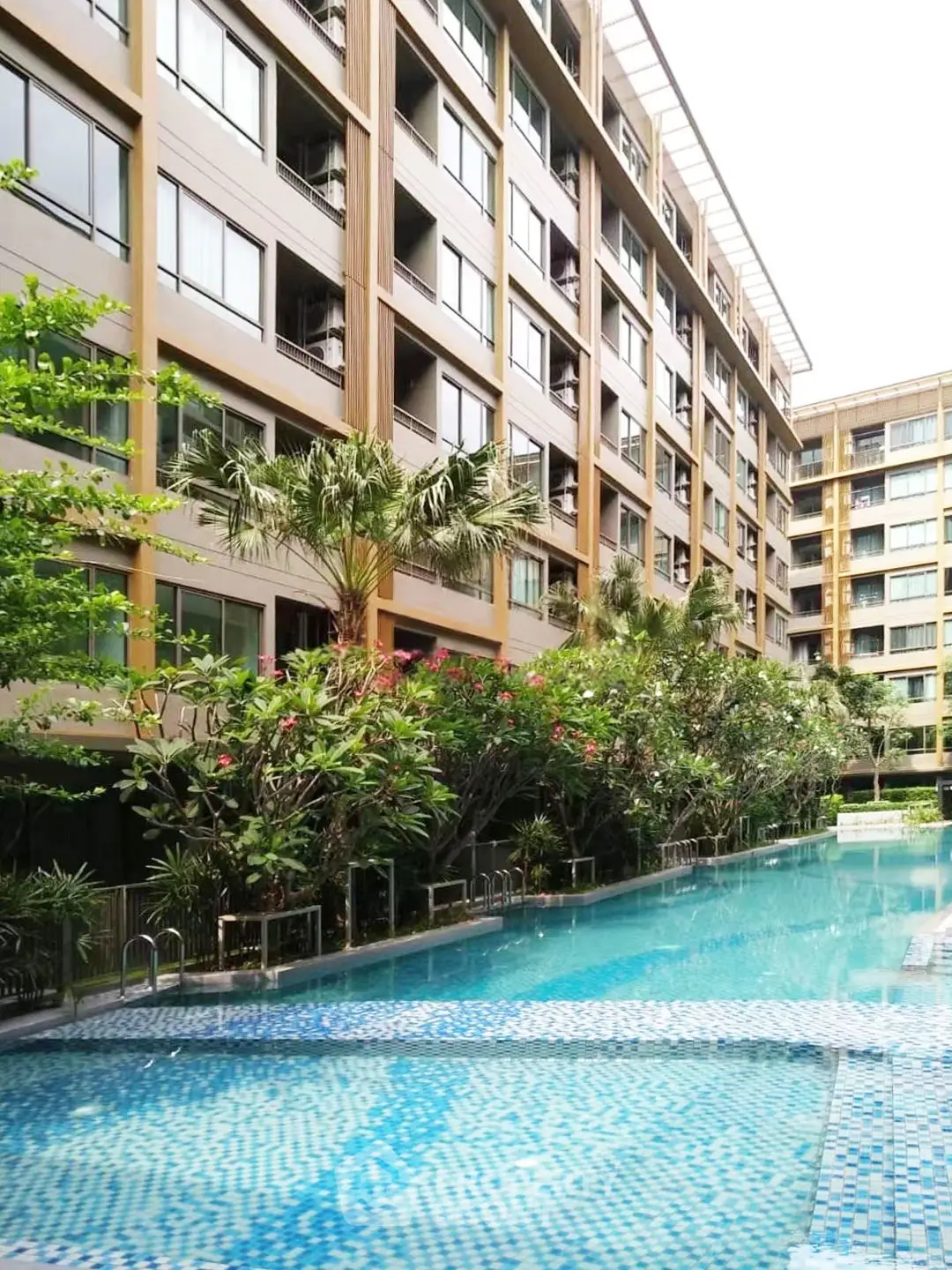 Luxurious apartment complex with stunning pool and lush greenery, perfect for modern living.