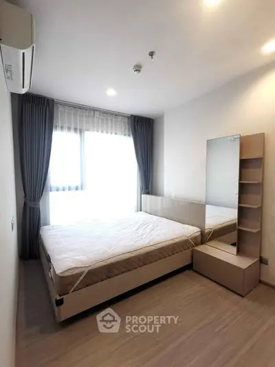 Modern bedroom with large window and stylish decor in a contemporary apartment.