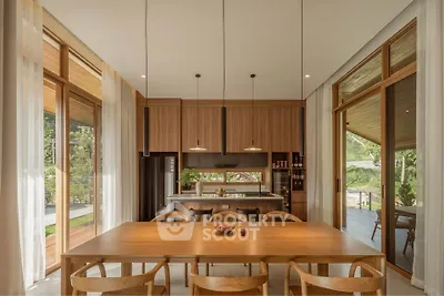 Spacious modern kitchen with wooden cabinetry and large dining table, featuring open layout and natural light.