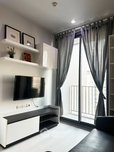 Modern living room with sleek TV setup and balcony view in urban apartment