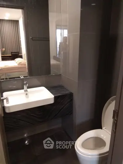 Modern bathroom with sleek design and view into a cozy bedroom