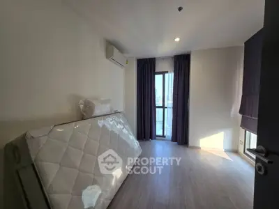 Spacious bedroom with natural light and air conditioning, featuring a large window and modern flooring.