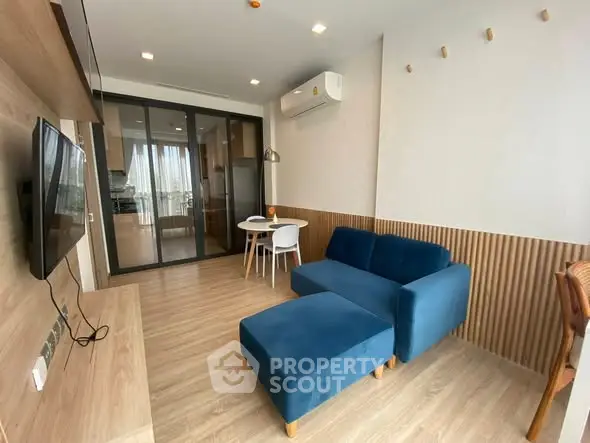 Modern living room with blue sofa and open kitchen layout, featuring stylish wood accents.