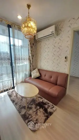 Charming living room with elegant chandelier and cozy sofa, featuring a stylish rug and air conditioning.