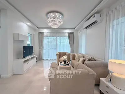 Elegant living room with plush sofas, modern chandelier, and large windows for natural light.