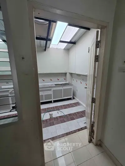 Spacious kitchen with open layout and ample natural light, featuring modern countertops and tiled flooring.