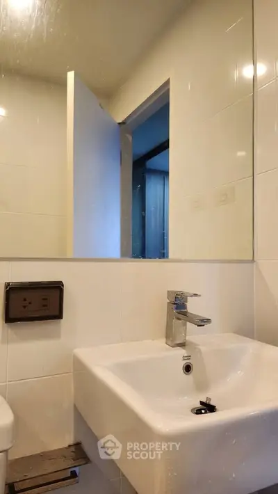 Modern bathroom with sleek sink and mirror in a minimalist design.