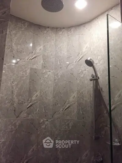 Luxurious marble-tiled bathroom with modern shower fixtures and recessed lighting.