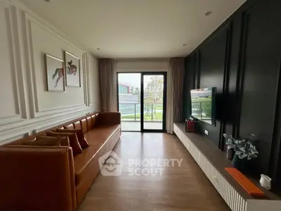 Stylish living room with modern decor and large window overlooking greenery.