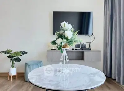 Modern living room with stylish decor and wall-mounted TV, featuring a marble table and elegant floral arrangement.