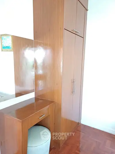 Elegant wooden wardrobe with built-in vanity in a bright room, perfect for stylish storage solutions.