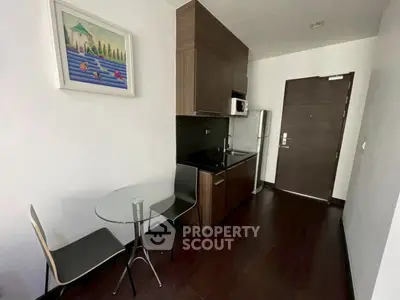 Modern compact kitchen with sleek cabinetry and dining area in a stylish apartment.