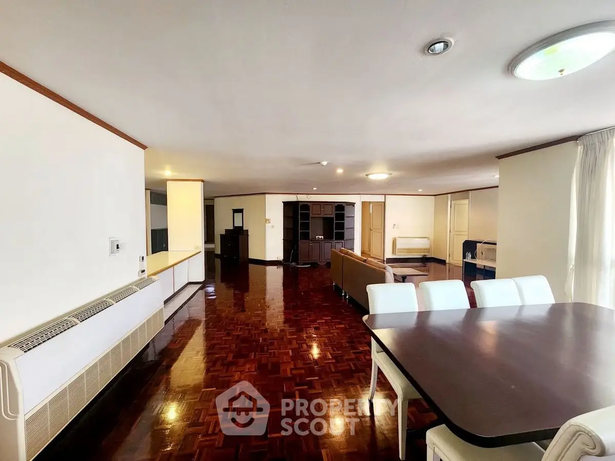 Spacious open-plan living and dining area with polished wooden floors and modern furniture.