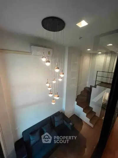 Modern living room with stylish pendant lights and loft-style staircase, perfect for urban living.
