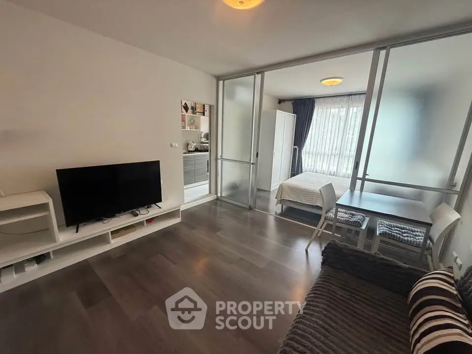 Modern studio apartment with open layout, featuring a cozy living area and bedroom separated by glass partitions.