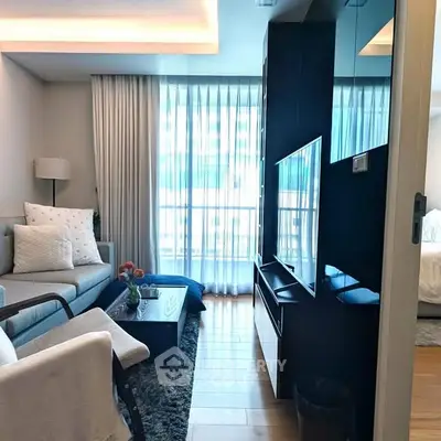 Modern living room with elegant decor and large windows offering natural light.