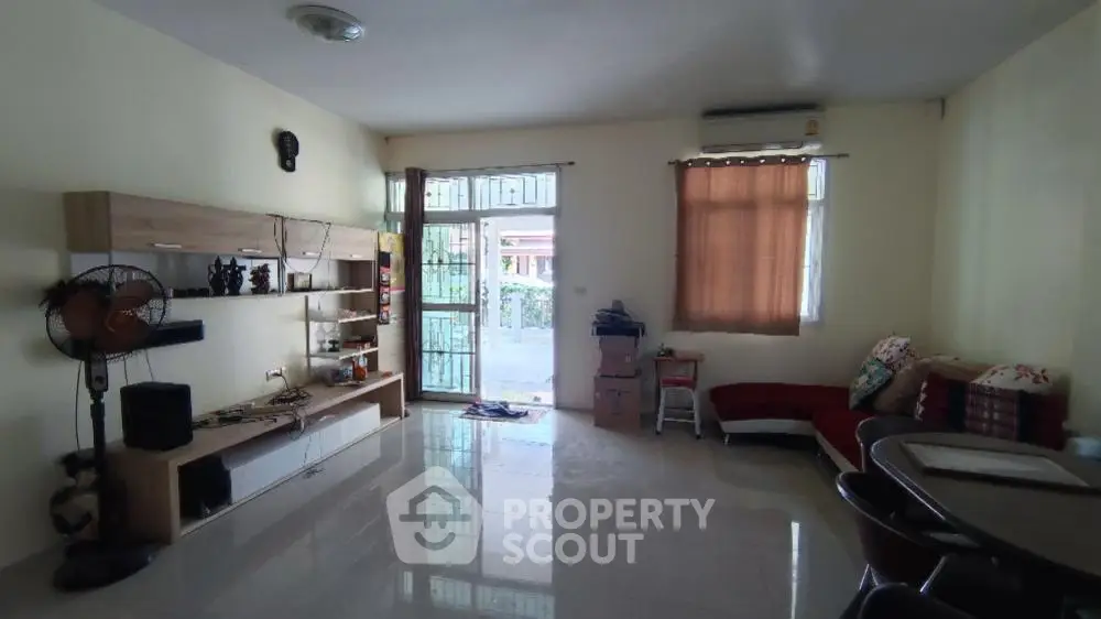 Spacious living room with glossy tiled flooring, ample natural light, and a cozy seating area, perfect for family gatherings and relaxation.
