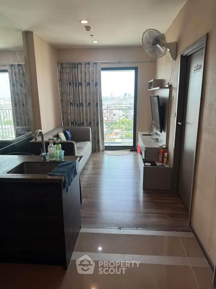 Modern living room with balcony view, sleek furnishings, and open layout in urban apartment.
