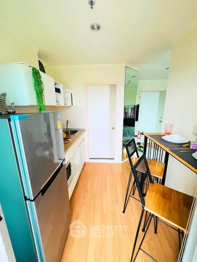 Modern kitchen with sleek appliances and cozy dining area in a stylish apartment.