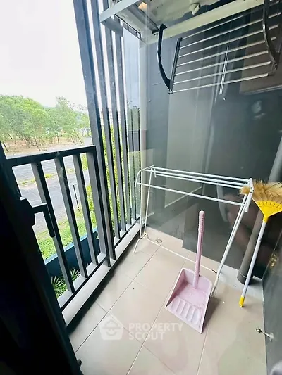 Compact balcony with cleaning tools and outdoor view, ideal for small apartments.