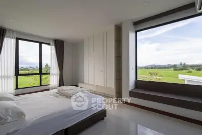 Spacious bedroom with large windows offering stunning green views, perfect for relaxation and tranquility.