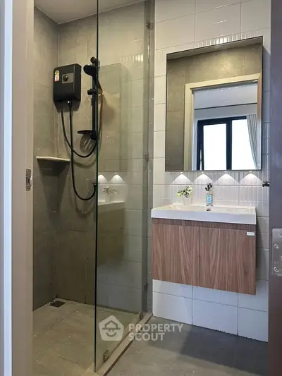 Modern bathroom with glass shower and sleek vanity in contemporary apartment.