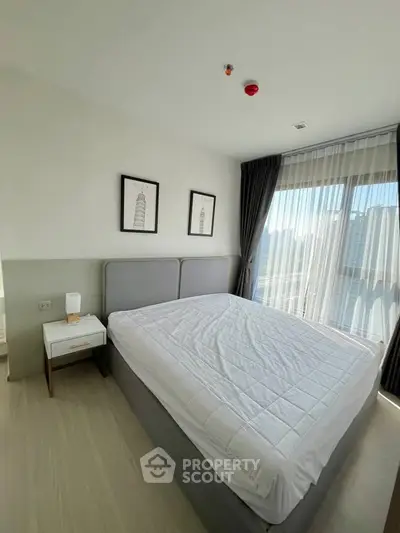 Modern bedroom with large window and stylish decor in a high-rise apartment.