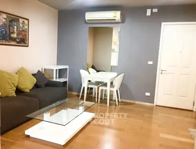 Modern living room with wooden flooring, stylish sofa, and dining area in open layout.