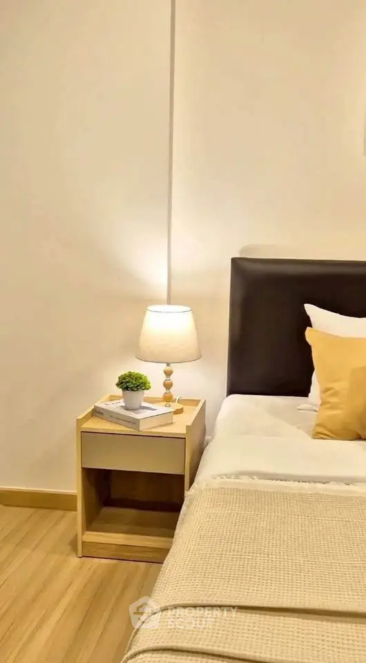 Cozy bedroom with modern decor and warm lighting, featuring a stylish bedside table and comfortable bedding.